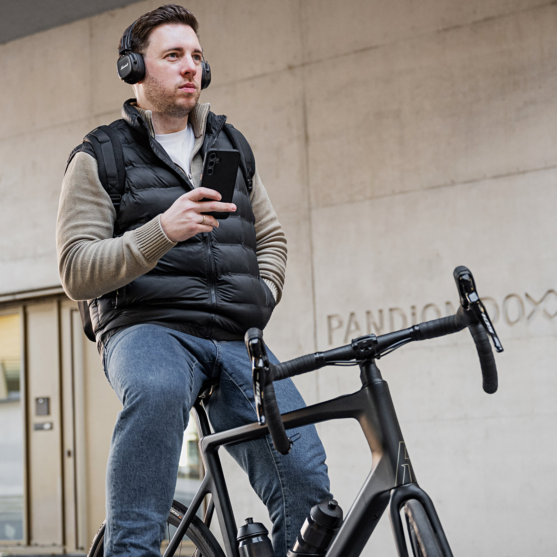 Mann auf Fahrrad in der Stadt hält NIVOcore Handyhülle in der Hand.