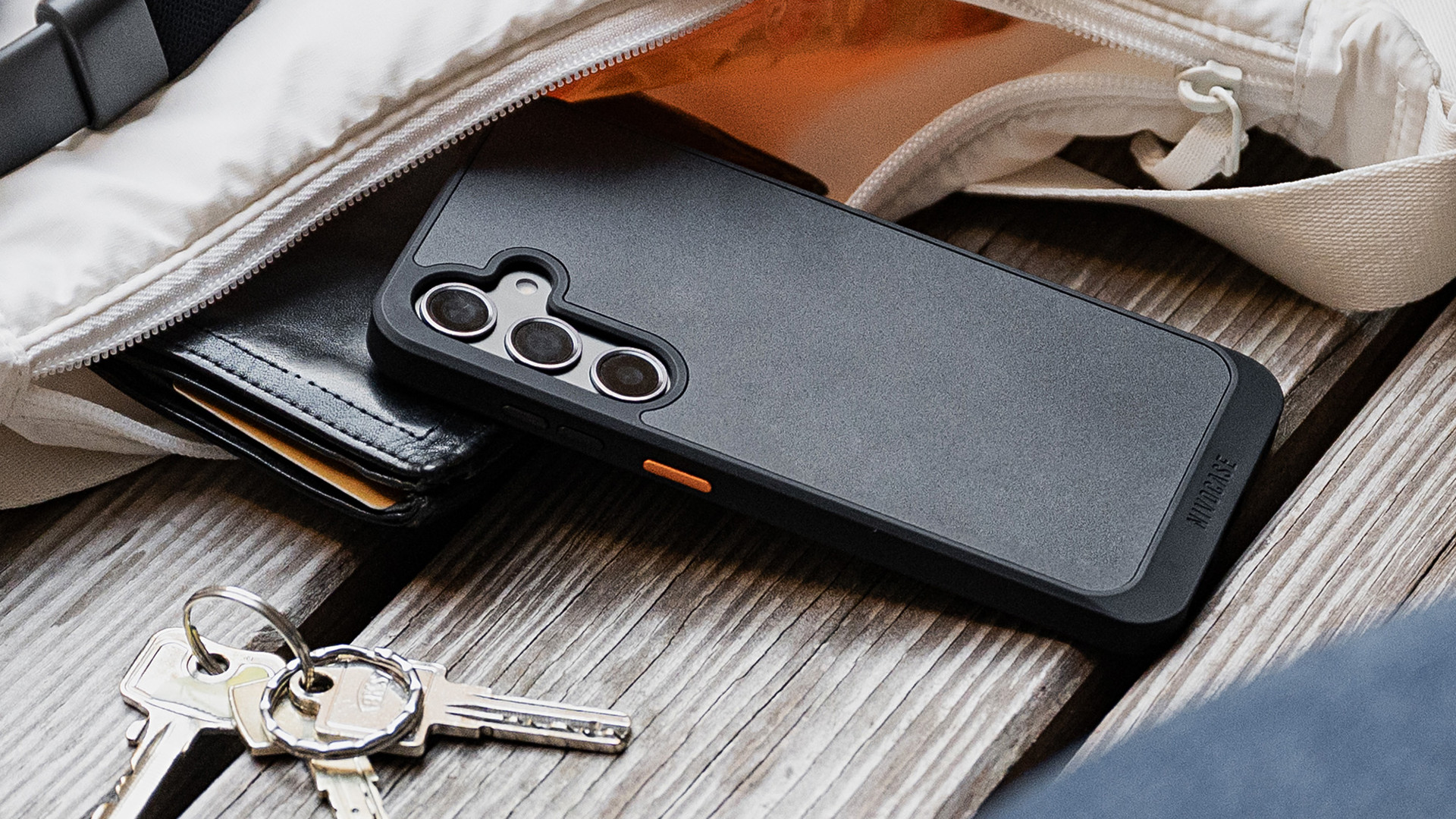 NIVOcore Handyhülle auf einer Holzbank mit Handtasche und Schlüssel in einer urbanen Umgebung.